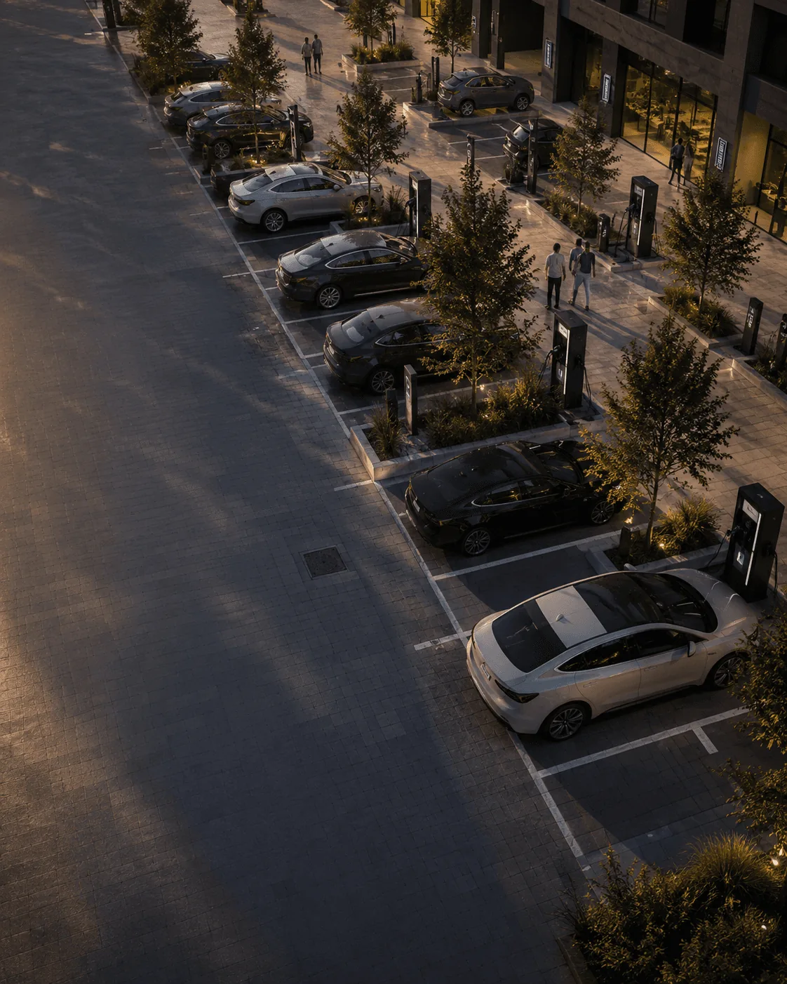 Parkplatz an einem Gebäude in der Abenddämmerung: Elektroautos stehen an einer Reihe beleuchteter Ladesäulen