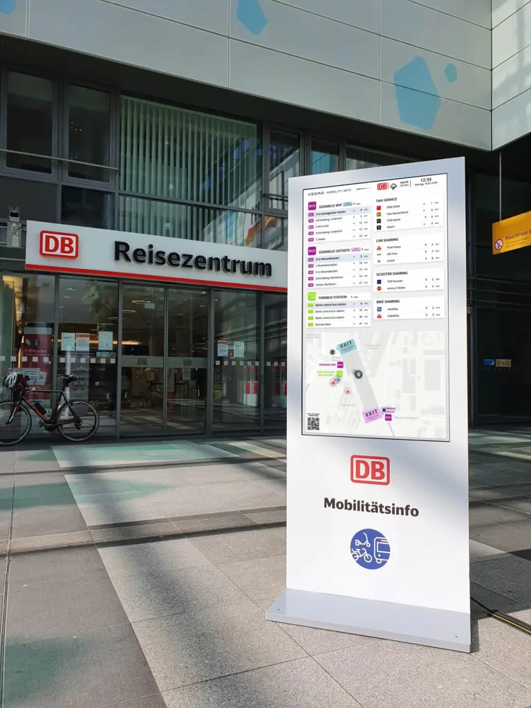 Der VEOMO-Mobilitätsmonitor im Einsatz – Für Bahnhöfe. Der Bildschirm zeigt Abfahrtszeiten von ÖPNV, Sharing-Angebote und eine Umgebungskarte.